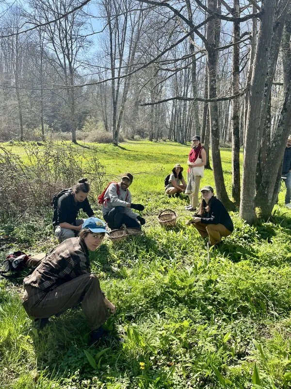 Un groupe accroupi dans l’herbe, paniers d’osier posés à côté
