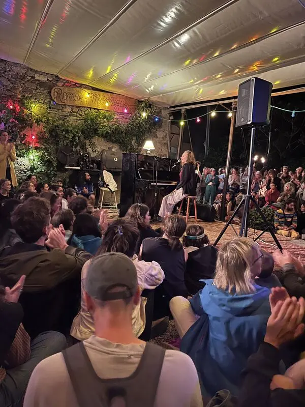 Une chanteuse sur scène au Café, le public assis devant elle